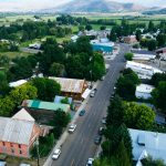 Halfway OR 14 Aerial view of Halfway, OR, with tree-lined streets, several cars parked along the road, and a mix of historic brick and modern buildings surrounded by green fields and distant hills.